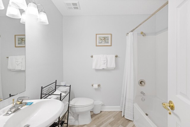 full bathroom featuring hardwood / wood-style flooring, toilet, shower / bath combo with shower curtain, and sink