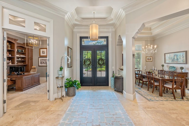 entrance foyer with an inviting chandelier, ornamental molding, a towering ceiling, and french doors