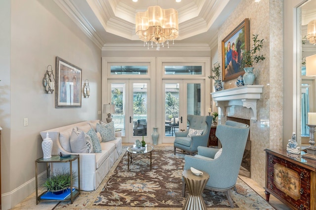 living area featuring a notable chandelier, ornamental molding, a tray ceiling, and french doors