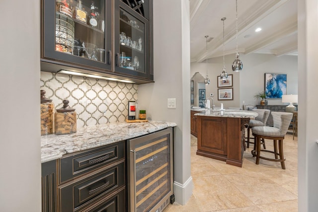 bar with wine cooler, tasteful backsplash, beamed ceiling, decorative light fixtures, and light stone counters