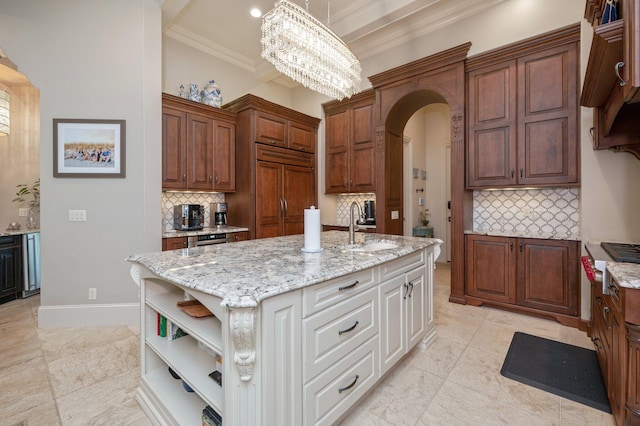 kitchen with sink, backsplash, paneled built in refrigerator, an island with sink, and white cabinets