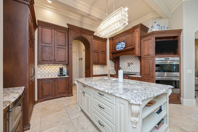 kitchen with decorative backsplash, a center island with sink, hanging light fixtures, and appliances with stainless steel finishes