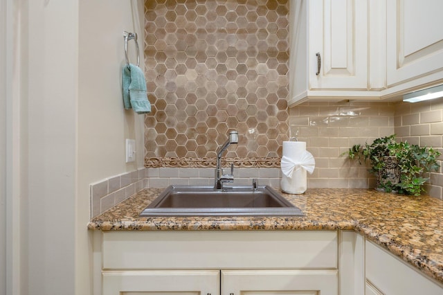 details featuring decorative backsplash, white cabinetry, sink, and stone counters