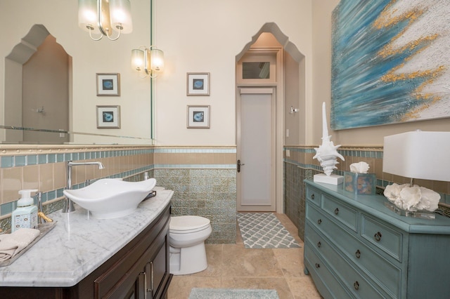 bathroom with vanity, tile walls, and toilet