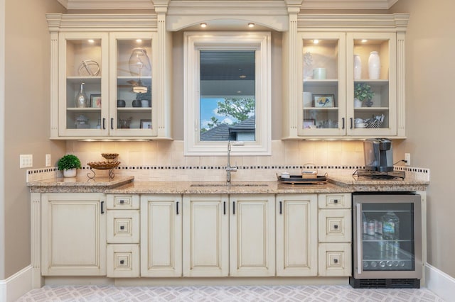 bar featuring light stone counters, sink, beverage cooler, and tasteful backsplash