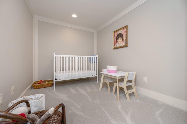 carpeted bedroom with ornamental molding and a nursery area