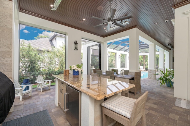 kitchen with light stone counters, a kitchen island, ceiling fan, wooden ceiling, and wine cooler