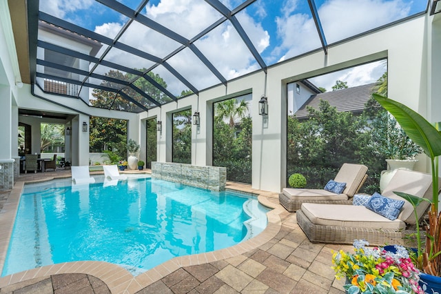 view of pool with pool water feature, glass enclosure, and a patio area