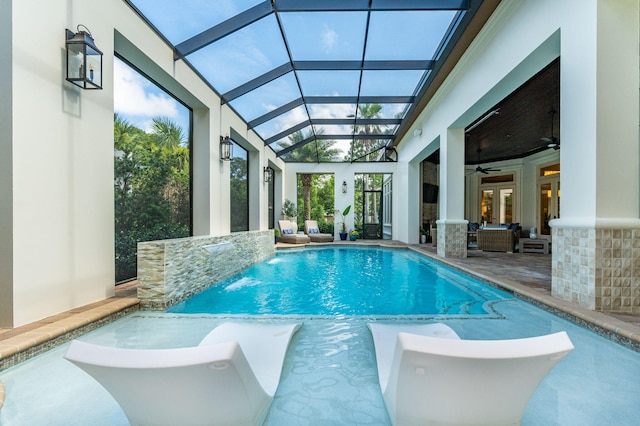 view of pool featuring a patio, glass enclosure, and ceiling fan