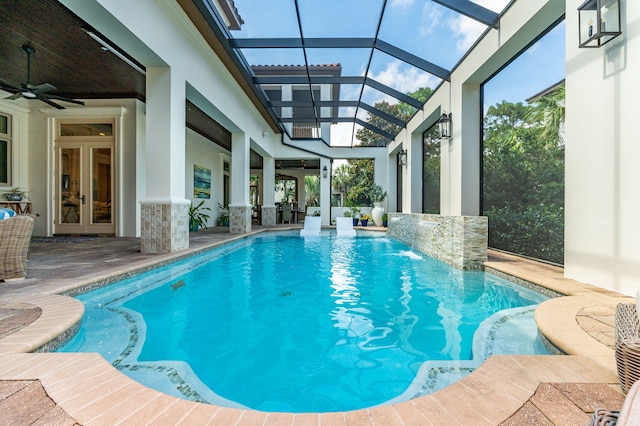 view of swimming pool featuring french doors, pool water feature, ceiling fan, glass enclosure, and a patio area