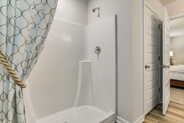 bathroom featuring a stall shower, connected bathroom, and wood finished floors