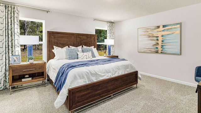 carpeted bedroom with a textured ceiling, multiple windows, and baseboards