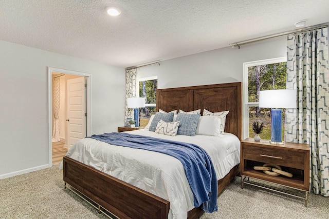 carpeted bedroom with connected bathroom, baseboards, and a textured ceiling