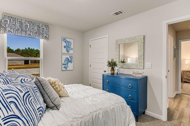 bedroom with visible vents, a textured ceiling, and baseboards