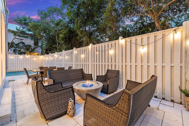 patio terrace at dusk with an outdoor living space with a fire pit