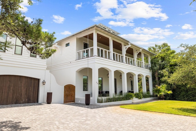 view of front of home with a balcony, a garage, a porch, and a front yard