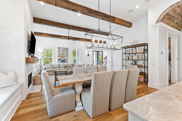 dining room with crown molding, beam ceiling, and light wood-type flooring