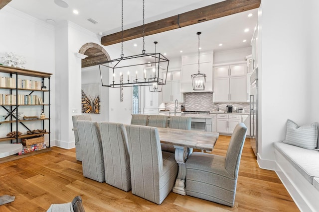 dining area with crown molding, beam ceiling, and light wood-type flooring