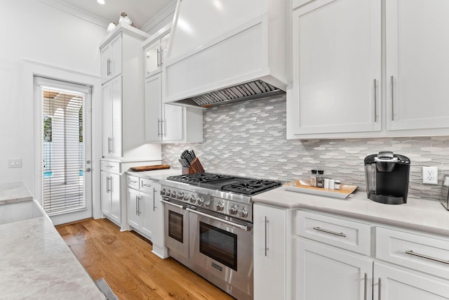 kitchen featuring range with two ovens, premium range hood, white cabinets, and light hardwood / wood-style floors