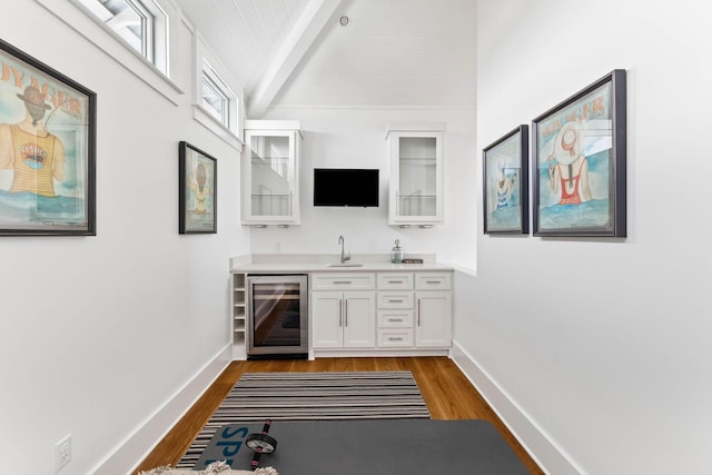 bar with wine cooler, sink, white cabinetry, and hardwood / wood-style floors