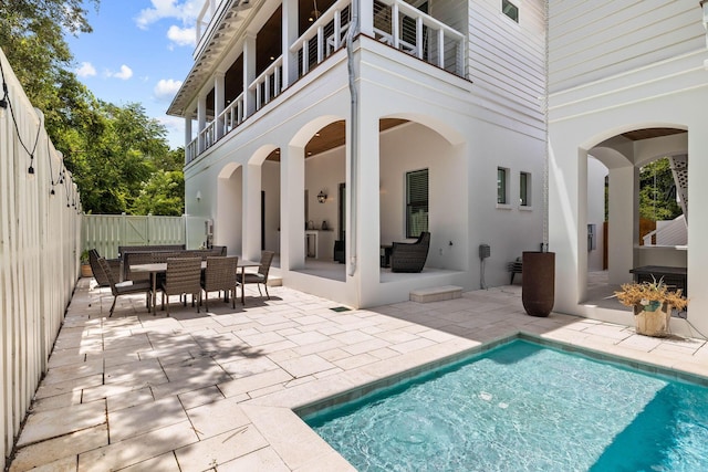 back of house with a fenced in pool, an outdoor hangout area, a patio, and a balcony