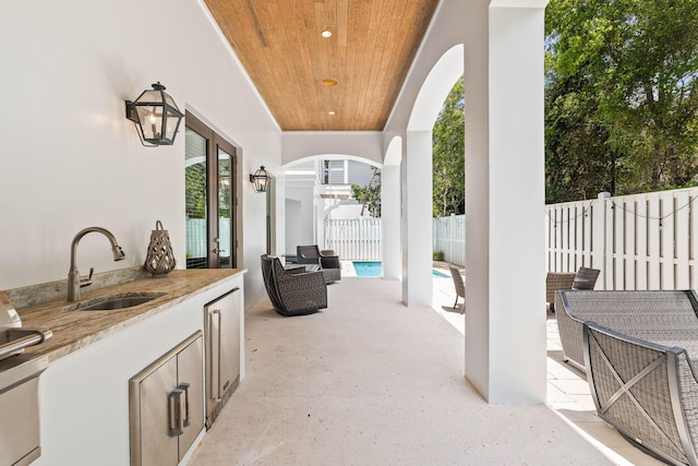 view of patio / terrace featuring exterior kitchen, sink, and a fenced in pool