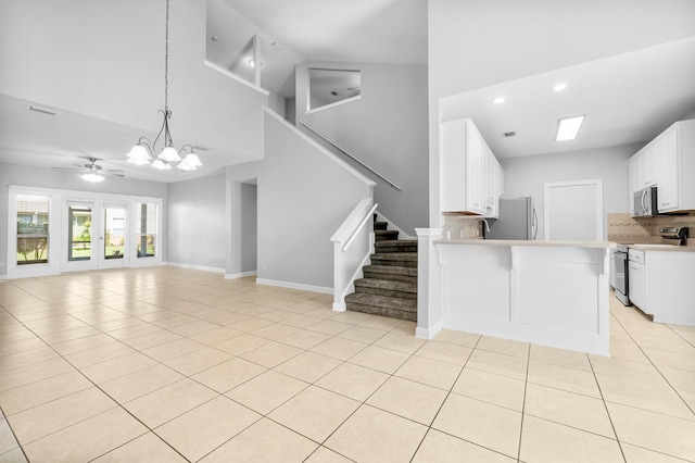 unfurnished living room with light tile patterned floors, a towering ceiling, ceiling fan with notable chandelier, and sink