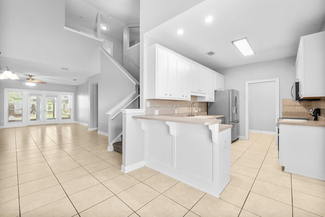 kitchen with ceiling fan, a kitchen bar, decorative backsplash, and kitchen peninsula