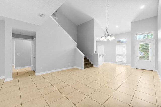 unfurnished living room featuring a notable chandelier, high vaulted ceiling, and light tile patterned flooring