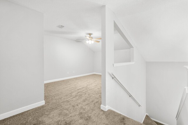 bonus room featuring lofted ceiling, ceiling fan, a textured ceiling, and carpet floors