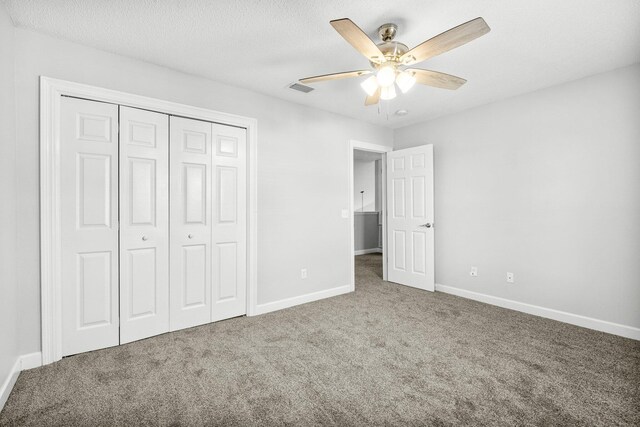 unfurnished bedroom with a textured ceiling, carpet, ceiling fan, and a closet