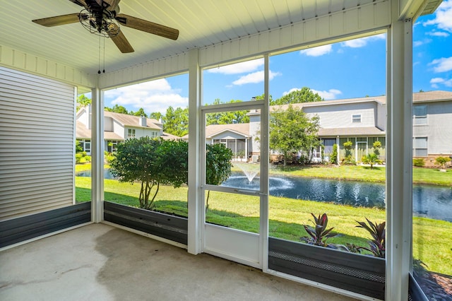 unfurnished sunroom featuring ceiling fan and a water view