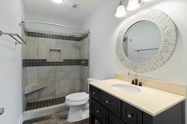 bathroom with vanity, a tile shower, wood-type flooring, and toilet