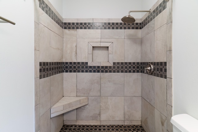 bathroom featuring tiled shower and toilet