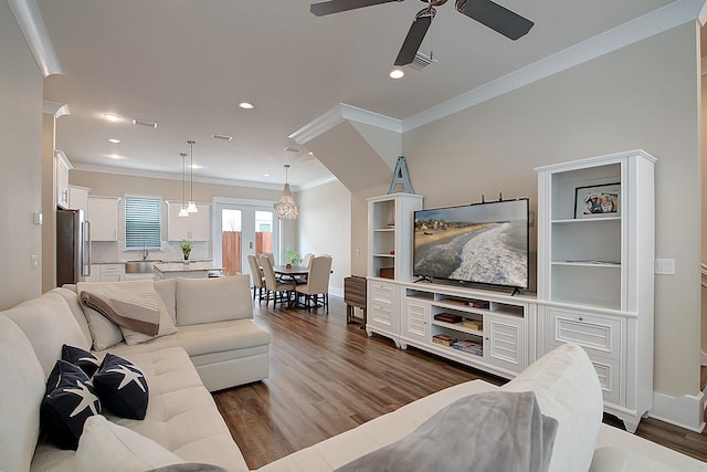 living room featuring ceiling fan, crown molding, sink, and dark wood-type flooring