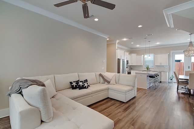 living room with ornamental molding, wood-type flooring, and ceiling fan