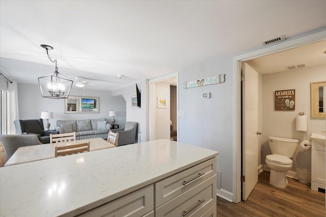 kitchen with hanging light fixtures, a notable chandelier, dark hardwood / wood-style flooring, and light stone counters