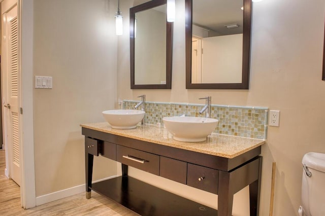 bathroom featuring tasteful backsplash, vanity, wood-type flooring, and toilet