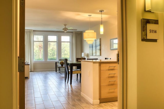 kitchen with light stone countertops, kitchen peninsula, hanging light fixtures, and ceiling fan