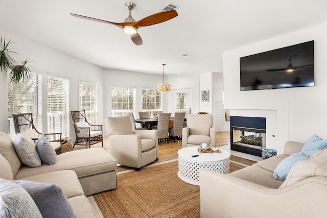 living room with a multi sided fireplace, light hardwood / wood-style floors, and ceiling fan