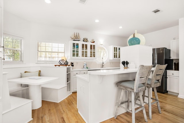 kitchen featuring a kitchen breakfast bar, a center island, white cabinetry, and light hardwood / wood-style flooring