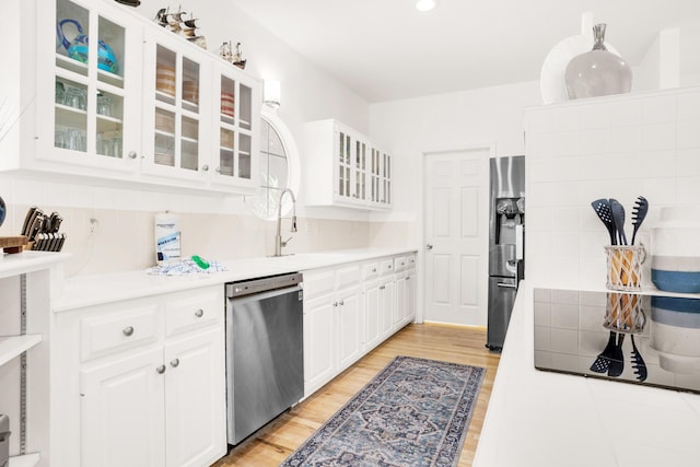 kitchen with sink, light hardwood / wood-style flooring, tasteful backsplash, white cabinetry, and stainless steel appliances