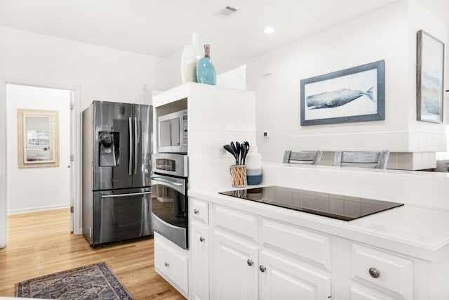 kitchen with appliances with stainless steel finishes, light hardwood / wood-style flooring, and white cabinetry