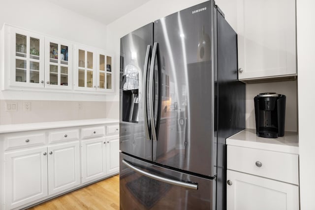 kitchen featuring decorative backsplash, white cabinetry, light wood-type flooring, and stainless steel fridge with ice dispenser