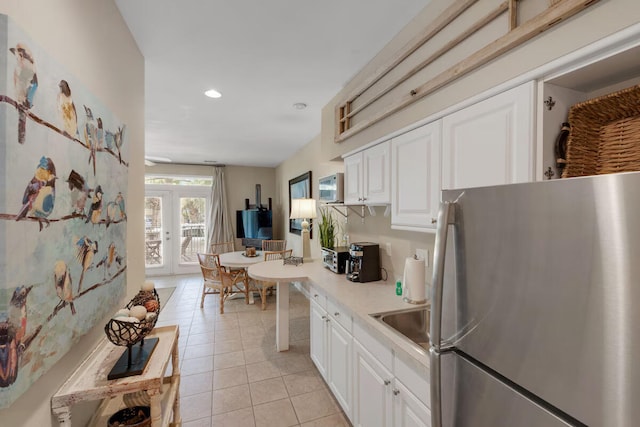 kitchen featuring light tile patterned flooring, white cabinetry, stainless steel refrigerator, and french doors