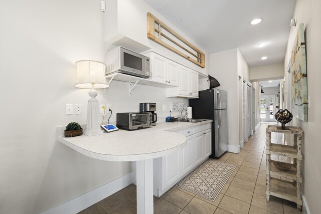 kitchen featuring stainless steel fridge, light tile patterned flooring, white cabinetry, and sink