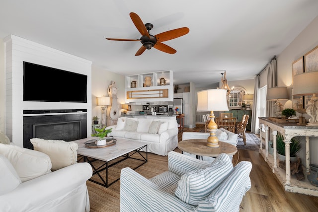 living room with dark wood-type flooring and ceiling fan with notable chandelier