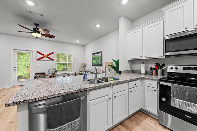 kitchen with kitchen peninsula, appliances with stainless steel finishes, sink, light hardwood / wood-style flooring, and white cabinetry