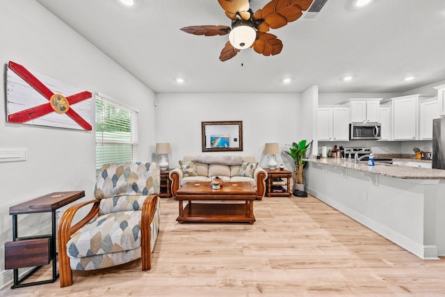 living room featuring light hardwood / wood-style floors, ceiling fan, and sink