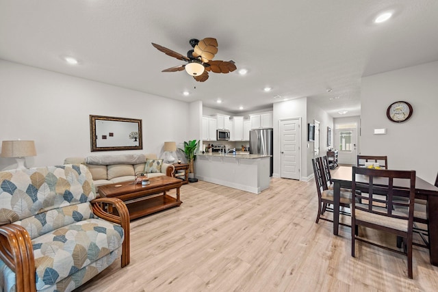 living room with ceiling fan and light hardwood / wood-style flooring